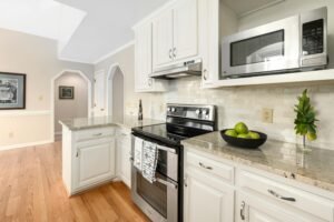 Bright and spacious kitchen featuring white cabinets, granite countertops, and stainless steel appliances.